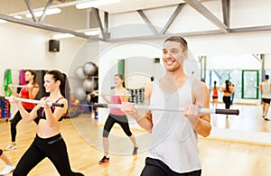 Group of smiling people working out with barbells