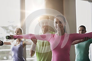 Group of smiling people working out with dumbbells