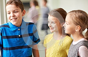 Group of smiling school kids talking in corridor