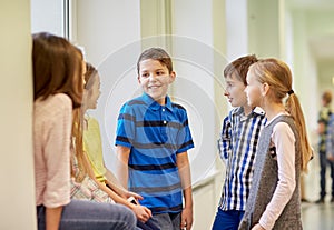 Group of smiling school kids talking in corridor