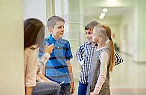 Group of smiling school kids talking in corridor