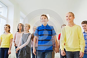 Group of smiling school kids walking in corridor