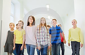 Group of smiling school kids walking in corridor