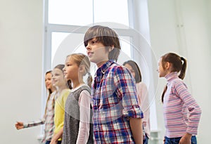 Group of smiling school kids walking in corridor