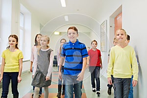 Group of smiling school kids walking in corridor