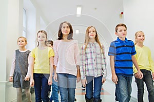 Group of smiling school kids walking in corridor