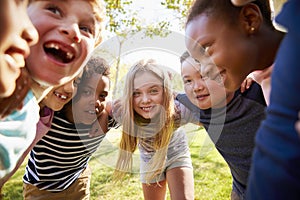 Group of smiling schoolchildren lean in to camera embracing