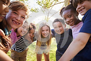 Group of smiling schoolchildren lean in to camera embracing