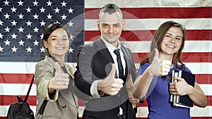 Group of smiling students giving thumbs up on american flag background