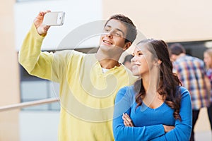 Group of smiling students with smartphone outdoors