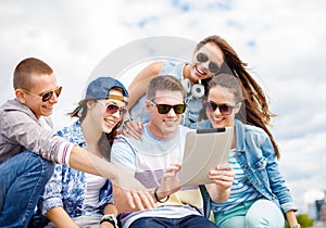Group of smiling teenagers looking at tablet pc
