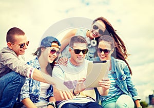 Group of smiling teenagers looking at tablet pc