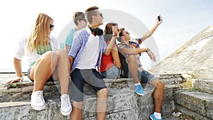 Group of smiling teenagers making selfie outdoors