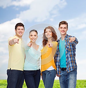 Group of smiling teenagers over blue sky and grass