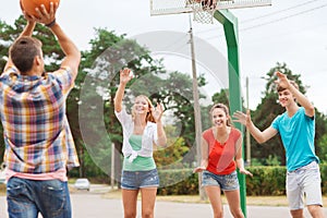 Group of smiling teenagers playing basketball