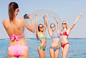 Group of smiling women photographing on beach