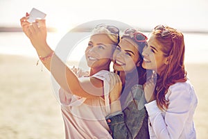 Group of smiling women taking selfie on beach