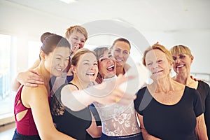 Group of smiling women taking selfies in a dance studio