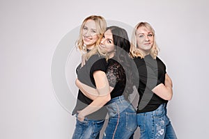 Group of smiling young friend woman hugging posing looking at camera at white studio background