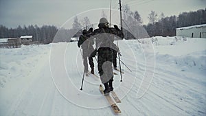 Group of soldiers run on skis in the woods with weapons. Clip. Soldiers with AK-47 rifles and grenade launchers running