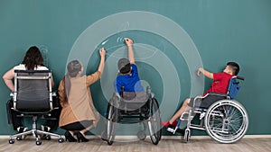 Group of special students in classroom, a down syndrome girl, two handicapped boys and cute Asian teacher drawing and painting on photo