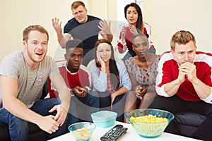 Group Of Sports Fans Watching Game On TV At Home