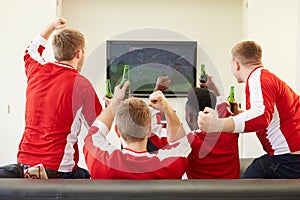 Group Of Sports Fans Watching Game On TV At Home