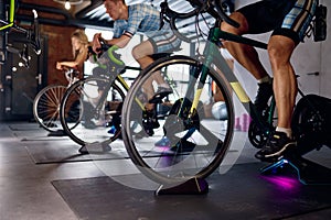 Group of sports people riding stationary bike at gym