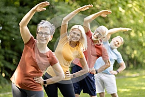 Group of sporty mature people doing stretching exercises at park