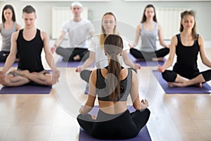 Group of sporty people doing Sukhasana exercise with instructor