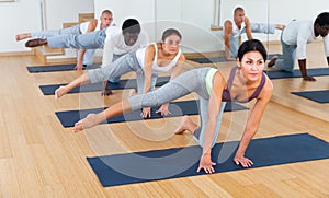 Group of sporty people practicing yoga positions during training