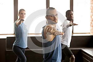 Group of sporty people standing in Warrior two exercise