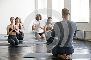 Group of sporty people in vajrasana exercise with instructor