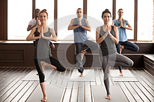 Group of sporty people in Vrksasana pose