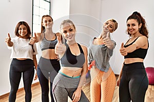 Group of sporty woman smiling happy doing ok sign with thumbs up at sport center