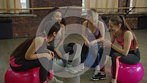 Group of sporty women relaxing on exercise balls at gym