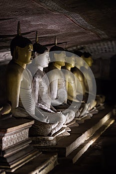 The group of statues of the Buddha in the Lotus position in a cave temple in Dambulla