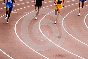 group stayer runners running middle distance race on turn track stadium