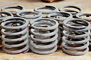 Group of steel springs of shock absorbers on wooden palete. Spare parts of heavy industrial machinery