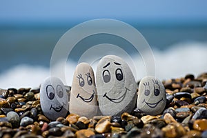 Group of stones with drawn faces in the sand. Father, mother, daughter and son. Concept of happy family.