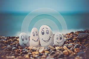Group of stones with drawn faces in the sand. Father, mother, daughter and son. Concept of happy family.