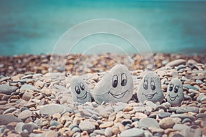 Group of stones with drawn faces in the sand. Father, mother, daughter and son. Concept of happy family.