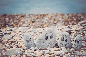 Group of stones with drawn faces in the sand. Father, mother, daughter and son. Concept of happy family.