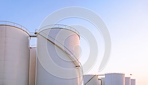 Group of storage fuel tanks in oil industrial manufacturing area against clear sky background in evening time