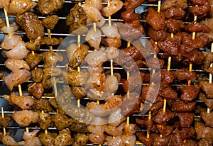 Group of strung meat flavored chicken on wooden skewers long pieces with hot peppers