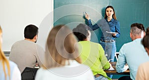 Group of students attentively listening to lecture of female teacher