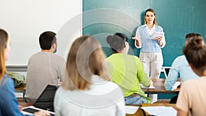 Group of students attentively listening to lecture of female teacher