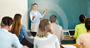 Group of students attentively listening to lecture of female teacher