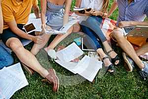 Group of students with books and tablet are studying outdoors together