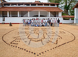 A group of students celebrating behind a big heart pattern made of Buddhist lamps